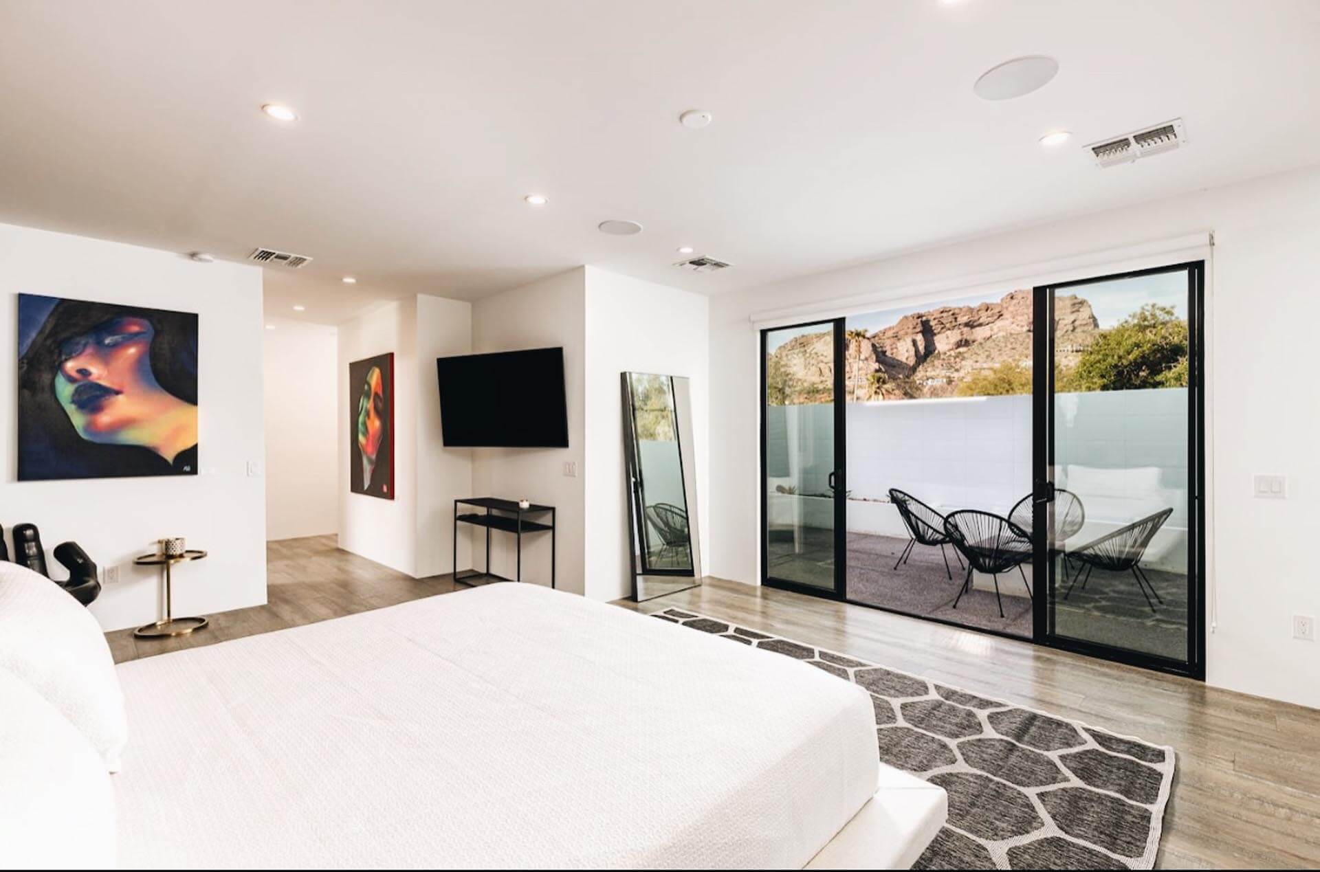 Serene and elegant white-walled bedroom at the Manor On Camelback, adorned with modern art and featuring a charming private patio for tranquil moments in Phoenix